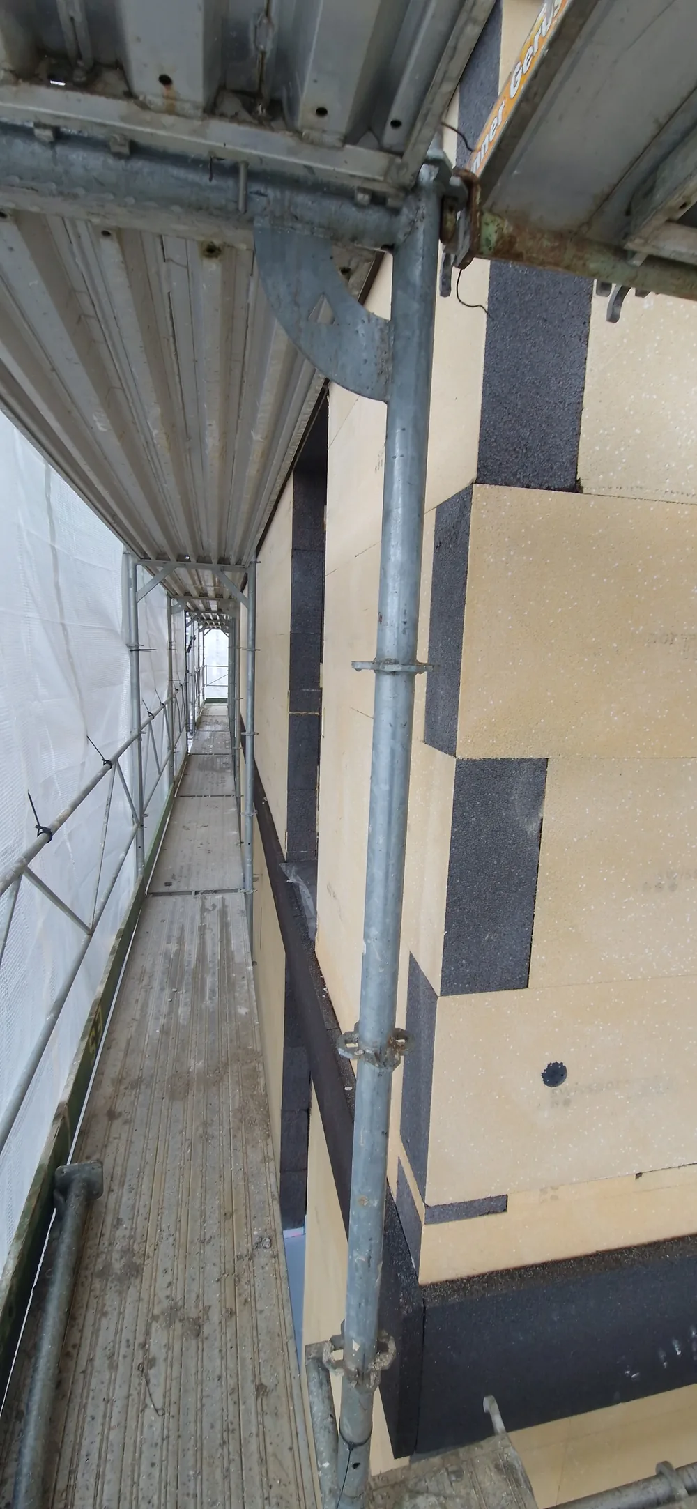 Panneaux isolants chevillés sur la façade, vus depuis l'échafaudage